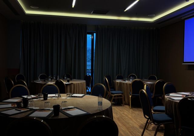 dark venue room with wooden floor and round tables set up