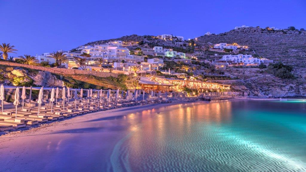 photo of beach at mykonos in the night with a vew of the city